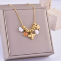 Collana a catena serpente dorata con ape e perle su un portagioie in velluto grigio - Stile Ape