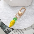 Vibrant corn-shaped resin keychain pendant with golden lobster clasp on a white tray - Corn