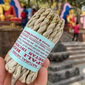 Traditional Tibetan rope incense with blue paper label held against temple background - Newari Forest Mist (50pcs)