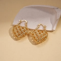 Dettaglio di orecchini a cuore dorati con trama intrecciata su sfondo di pietra - Fibbia per orecchie / Oro