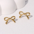 Minimalist golden bow stud earrings in stainless steel on white decorative block - Gold