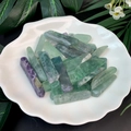 Macro view of polished green and purple fluorite crystal bars on a decorative shell plate - Fluorite