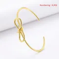 Detail view of gold-plated twisted bow bangle with a 2.0mm wire diameter specification - Gold Style (Smooth Surface)