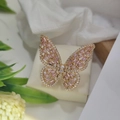 Close-up of golden butterfly ring with pink rectangular gems and white sparkling crystals - Gold Pink Zircon
