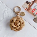 Detail of champagne gold camellia keychain in lychee grain leather with a coin charm - Gold