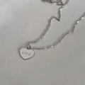 Macro shot of silver heart pendant featuring three small engraved hearts on flat metal chain - Minimalist Heart Necklace