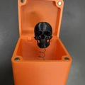 Vista macro di un teschio stampato in 3D in una scatola regalo a sorpresa arancione - Scatola Sorpresa Teschio Halloween