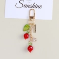 Detail of red persimmon keychain with green leaf and gold clasp for bags - Berry Pendant