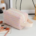 Close-up of pink tweed makeup bag with woven texture, zipper, and fabric handle - Pink