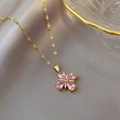 Macro-detail van de gouden klaverketting met roze druppelvormige stenen op zijde - Roze Klaver (Gouden Ketting)