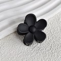Close-up of matte black flower hair claw clip on a minimalist white stone background - Black