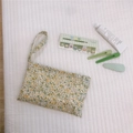 Detailed flat lay of floral cotton pouch with matching green accessories on soft white quilt - Light Yellow Floral