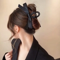 Detail of a large black satin bow hair claw clip worn on a low bun hair style - Black Bow (Matte Clip 11cm)