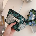 Dettaglio della mini pochette in tessuto jacquard a fiori con etichetta in stoffa - Base Nera con Fiori Verde Scuro e Bianchi