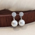 Macro shot of vintage pearl drop earrings with zircon studs on a wooden display - Full Diamond Round Large Pearl Dangle Earrings