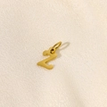 Detailed macro view of a gold Z letter pendant on a sparkling beige fabric background - Letter-Z