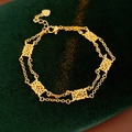 Macro shot of gold vintage flower bracelet with intricate hollowed petals on green fabric - Gold