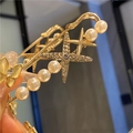 Detail of a gold safety pin brooch with sparkling stars, pearls, and a yellow butterfly - Golden Four-Pointed Star Cat's Eye Butterfly Brooch (7.5cm)