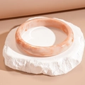 Primer plano de brazalete de resina marmoleada naranja sobre base de piedra natural - Estilo Fino Con Patrón de Mármol / Rosa Blanco