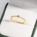 Close-up of gold-plated H letter ring with diamond-encrusted band in a green velvet box - Gold H