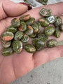 Primo piano di pietre di unakite ovali lucide per gioielli fai-da-te in mano - 30*40mm / Unakite