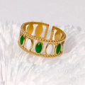 Vue macro d'une bague ouverte dorée avec émail ovale vert et blanc sur support blanc - Or Blanc Vert