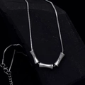 Collar de cadena de serpiente plateada con tres colgantes cilíndricos sobre una roca oscura - 45+5cm