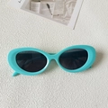 Detail of mint green cat-eye sunglasses with oval frames and dark lenses on white background - Green