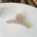 Close-up of a glossy beige curved hair claw clip on a minimalist white surface - Light Nude Pink