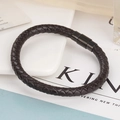 Close-up of a dark brown braided leather bracelet with black magnetic metal clasp on desk - Brown Leather Black Buckle