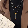 Collana a doppio strato in maglia snake dorata con tre perle occhio di tigre e nappa a Y - Collana a Doppio Strato con Ciondolo in Occhio di Tigre Sfumato