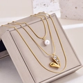 Three-layer gold necklace with white pearl and sparkling heart pendant on a jewelry box - Rhinestone Heart