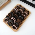 Macro shot of assorted brown, grey, and black elastic hair ties on a bamboo tray - 50 Pieces / Dark Mixed