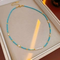 Close-up of turquoise and freshwater pearl necklace in jewelry box with golden light - Blue