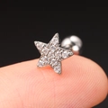 Macro shot of silver star cartilage earring with zircons on a finger for size scale - Pentagram / Silver (Star)