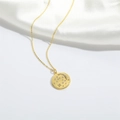 Detailed macro of gold celestial pendant necklace with moon and star relief on white silk - Moon & Star