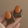 Detalle de pendientes vintage de resina con diseño geométrico oval naranja y cuadrado marrón - Marrón
