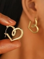 Pair of gold heart-shaped hoop earrings in stainless steel held by hand for detail - 18K Gold Heart (0441)