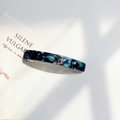 Macro detail of acrylic hair clip with blue marble pattern and silver metal clasp - Violet Blue