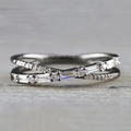 Close-up of silver criss-cross ring featuring micro-pave round and baguette cut diamonds - US 5 / Black & Gold