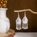 Close-up of ethnic silver hollow teardrop earrings with metal tassels on a branch - Silver Hollow Drop Tassel Style 3(E2875-11)