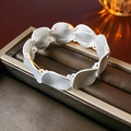 Vista macro di un bracciale a maglie argento opaco con pezzi metallici curvi minimalisti - Argento