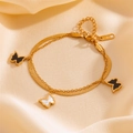 Pulsera de doble capa de acero inoxidable dorado con dijes de mariposa sobre tela de satén - Pulsera / Dorado