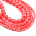 Macro shot of assorted round coral pink stone beads with natural white band textures - Red Striped Turquoise Style