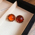 Close-up of amber textured round stud earrings in irregular gold frames within a jewelry box - 24# Silver Earring Post - Amber Gold Stud Style