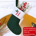 Green knit Christmas stocking with red letter H embroidery hanging on a fireplace - Letter H / Dark Green