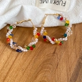 Dettaglio ravvicinato di orecchini a cerchio con cristalli e perle su tessuto bianco - Perno in Argento Multicolore Stile Piccolo