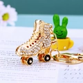 Goldener Schlittschuh-Schlüsselanhänger mit funkelnden Strasssteinen und schwarzen Rädern - Weiß