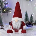 Nordic Christmas gnome with red hat and white beard in a snowy winter holiday scene - Red Sitting Doll