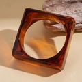 Macro shot of an amber acrylic square bangle with tortoise shell texture on beige background - Brown